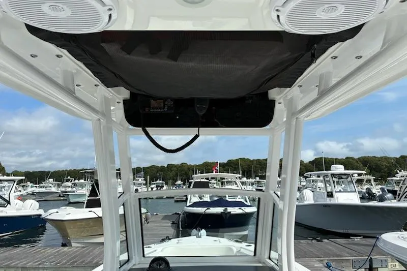 Slide: The Image of 2022 Edgewater 230CC boat interior with speakers, docked at marina with other boats. - 8