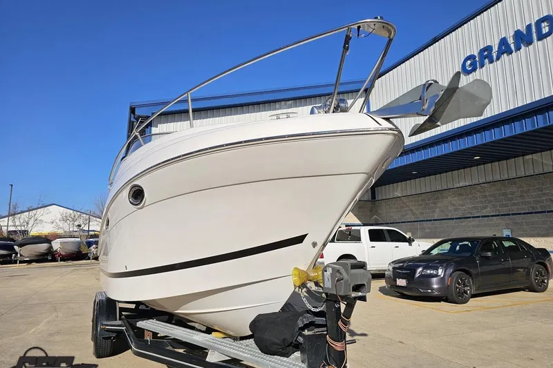 Slide: The Image of 2008 Four Winns V258 boat on trailer, parked outside dealership under clear blue sky. - 10