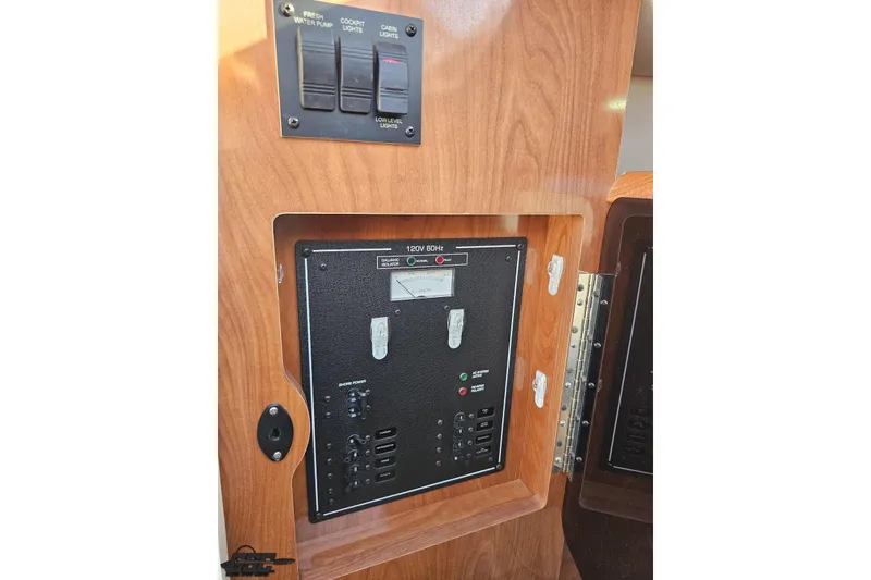 Slide: The Image of 2008 Four Winns V258 electrical panel with switches and controls in wooden cabinet. - 60