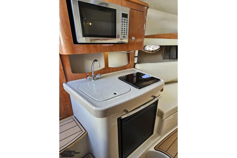 Slide: The Image of 2008 Four Winns V258 boat interior with kitchenette, featuring microwave, sink, and stove. - 65