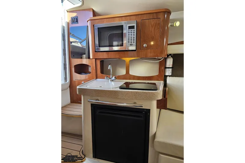 Slide: The Image of 2008 Four Winns V258 boat interior with kitchenette, featuring microwave, sink, and mini-fridge. - 71