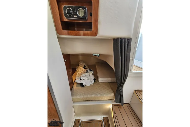 Slide: The Image of 2008 Four Winns V258 cabin interior with bed, wood accents, and stereo system. - 76