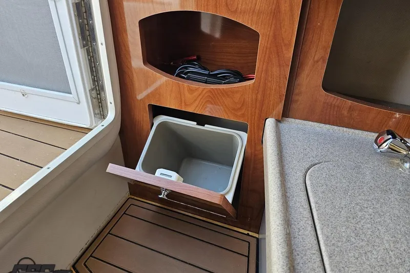 Slide: The Image of 2008 Four Winns V258 interior with wooden cabinetry and built-in trash compartment. - 80