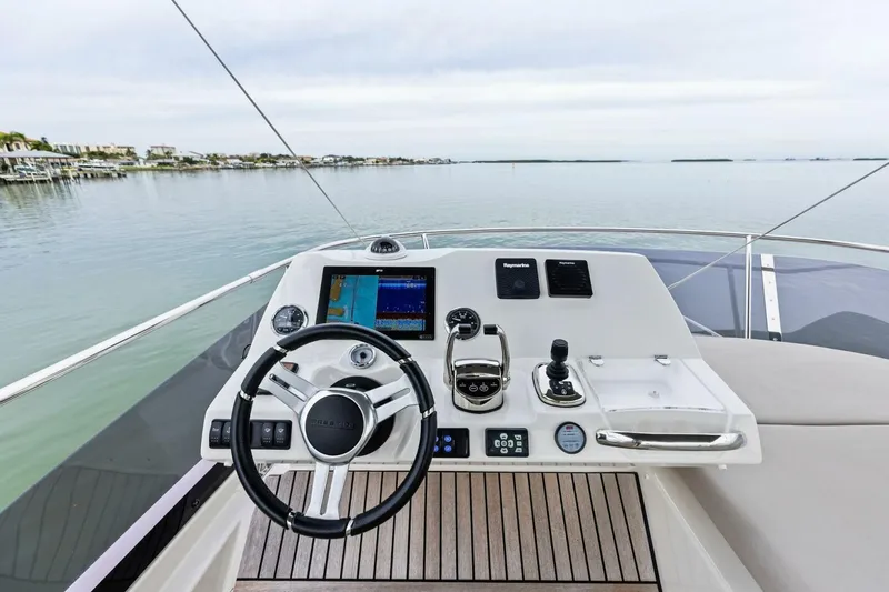 Slide: The Image of Helm of 2022 Prestige 420 yacht with modern navigation controls and serene water view. - 41