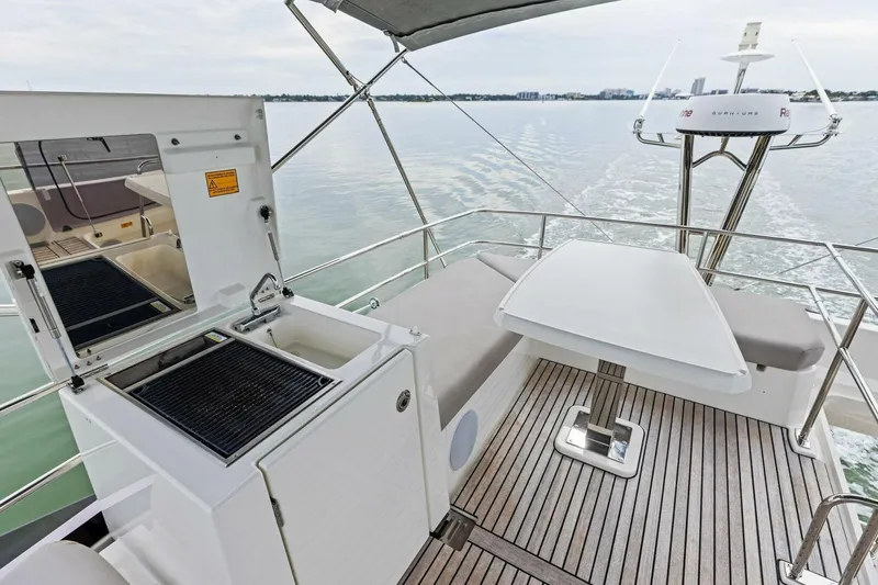 Slide: The Image of 2022 Prestige 420 yacht deck with grill, table, and seating on calm water. - 43