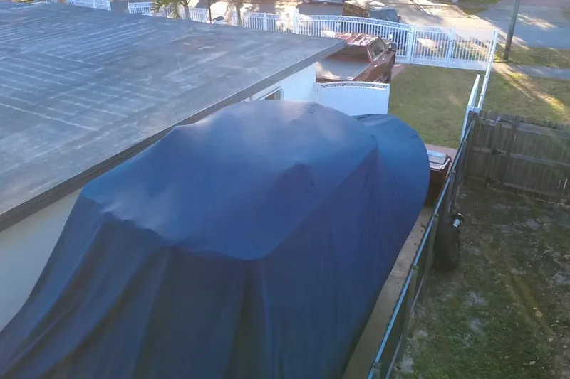 Slide: The Image of Covered 2007 Grady-White Bimini 306 boat beside a house, under a blue tarp. - 11