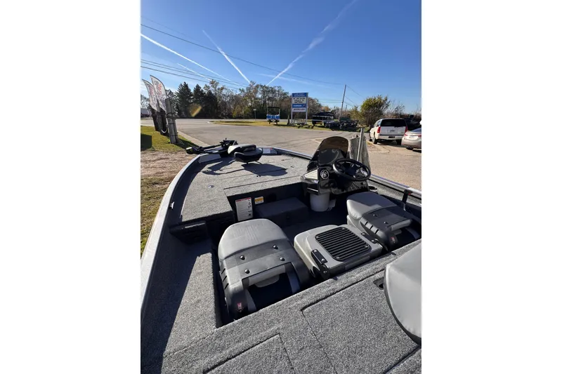 Slide: The Image of 2026 Lowe Stinger 175C boat interior with steering console and seating, parked outdoors. - 12