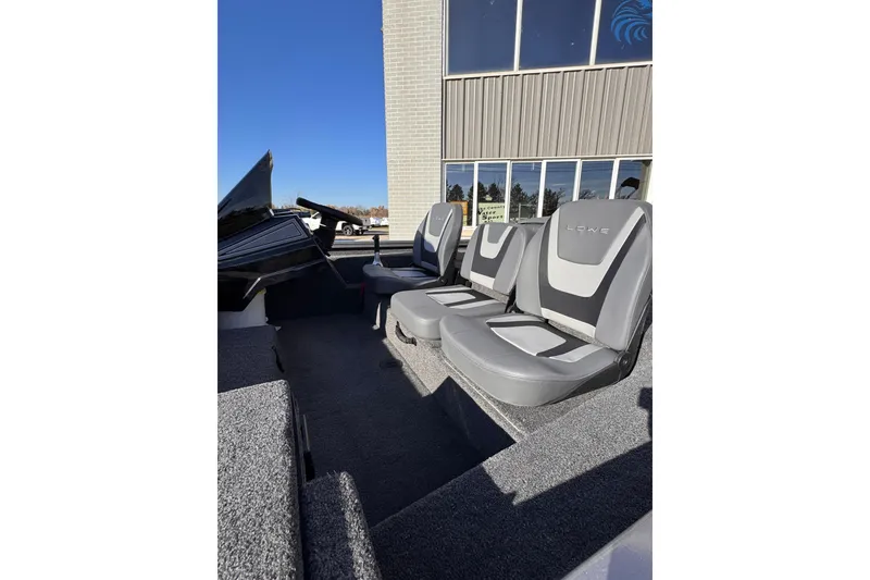 Slide: The Image of 2026 Lowe Stinger 175C boat interior with gray seating, parked outdoors. - 13