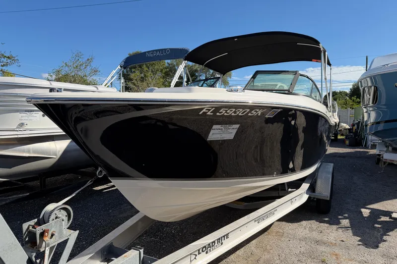 The Image of 2019 NauticStar 2302 Legacy Dual Console boat on trailer, black hull, sunny day. - 0