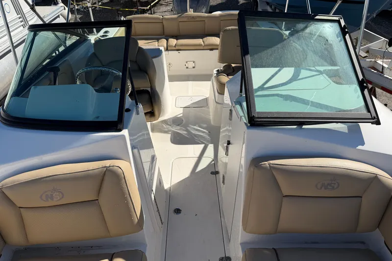 Slide: The Image of 2019 NauticStar 2302 Legacy Dual Console boat interior with beige seating and open windshield. - 1