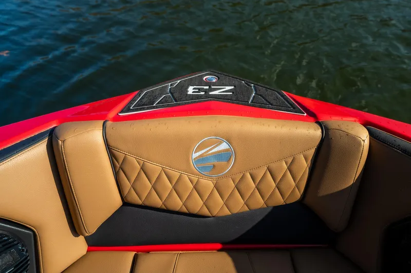Slide: The Image of 2026 Tigé Z3 boat interior with tan diamond-stitched upholstery and logo, near water. - 17