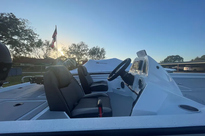 Slide: The Image of 2026 Xpress H20C Crappie boat interior with steering wheel and seats at sunset. - 4