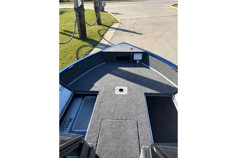 Slide: The Image of 2026 Lowe Fishing Machine 1775WT boat interior with carpeted deck and storage compartments. - 10