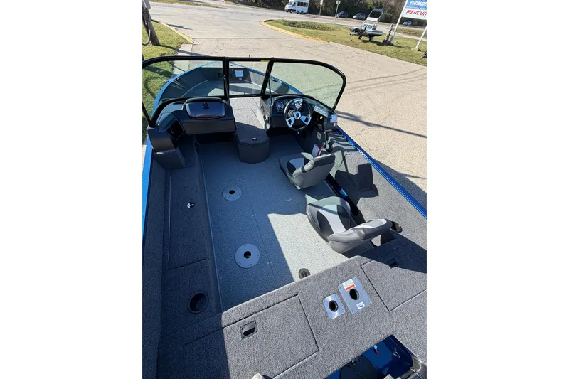 Slide: The Image of 2026 Lowe Fishing Machine 1775WT interior with seating and dashboard, parked outdoors. - 4