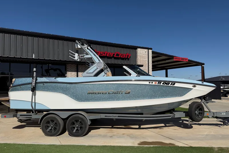 Slide: The Image of 2022 MasterCraft XT24 boat on trailer outside dealership. - 1