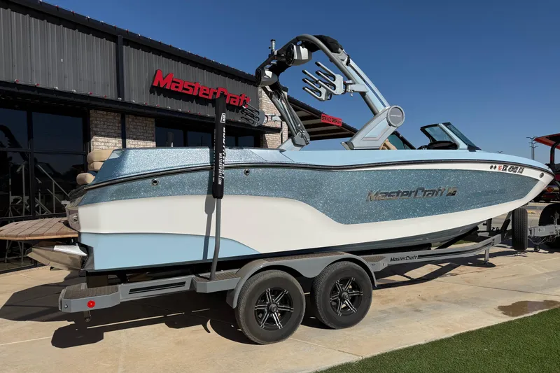 Slide: The Image of 2022 MasterCraft XT24 boat on trailer outside dealership, showcasing sleek design and modern features. - 2
