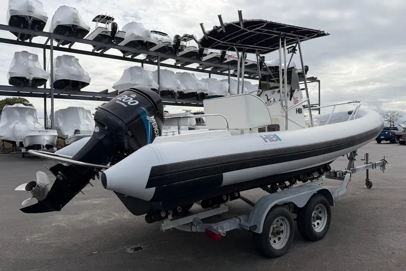 Slide: The Image of 2006 HBI 22 boat on trailer with Mercury 200 engine, parked near stacked boats. - 4