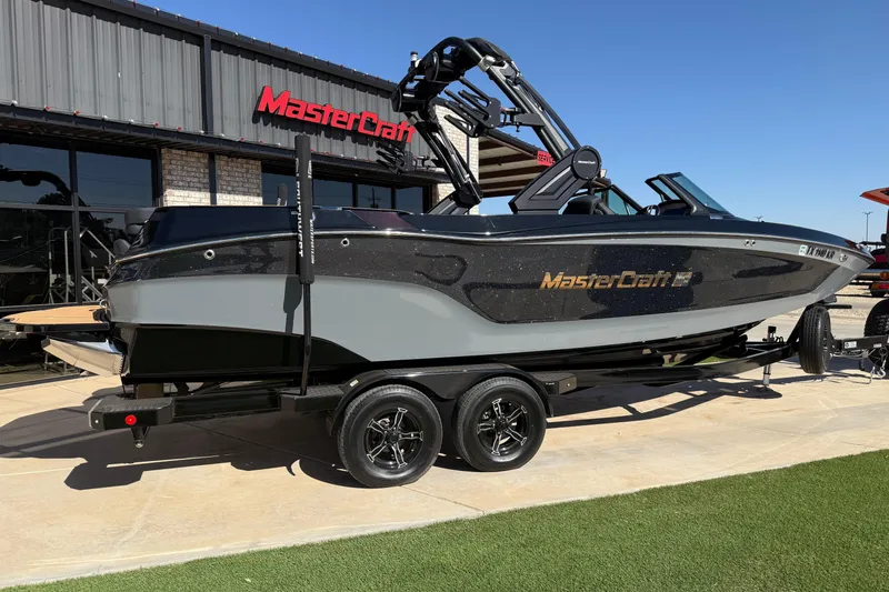 Slide: The Image of 2023 MasterCraft XT24 boat on trailer outside dealership. - 2