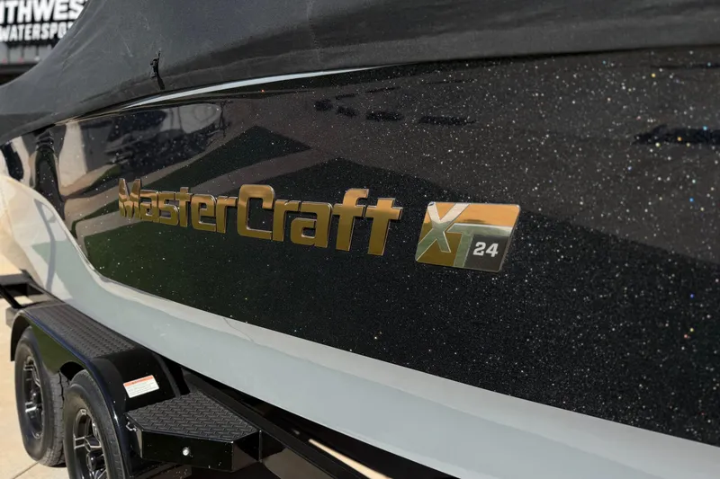 Slide: The Image of 2023 MasterCraft XT24 boat with sleek black and white design, parked on a trailer. - 5