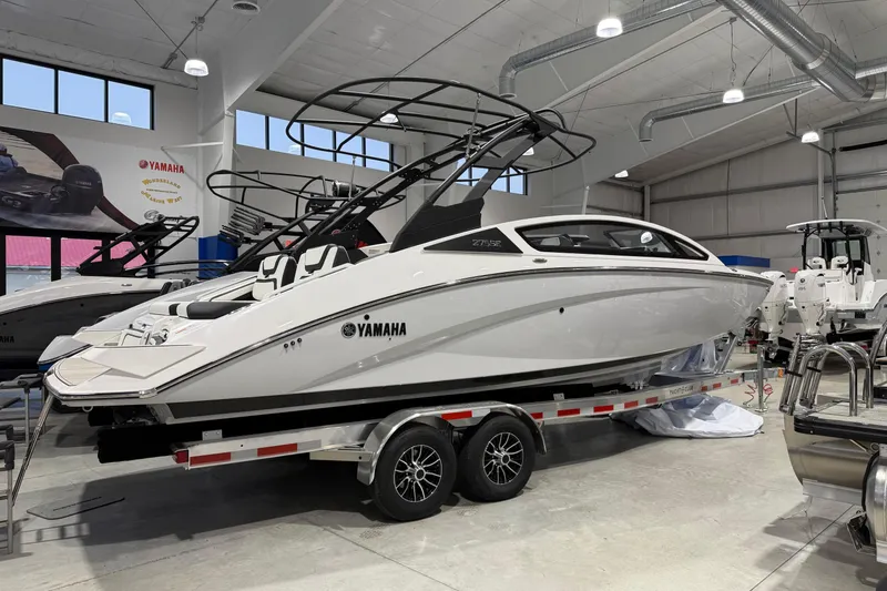 The Image of 2025 Yamaha Boats 275SE in showroom, sleek white design on trailer. - 0