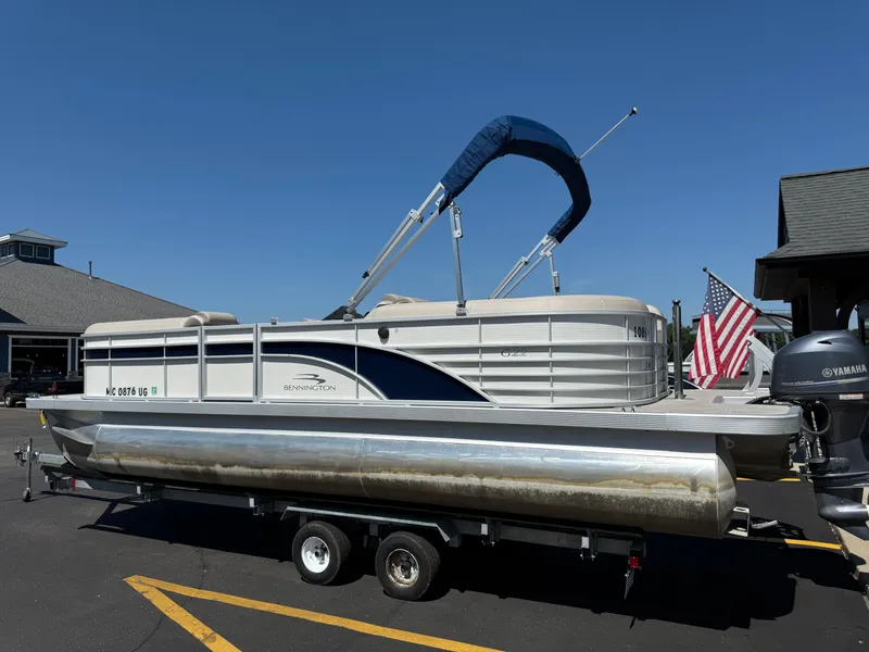 Slide: The Image of 2017 Bennington G22 pontoon boat on trailer, parked outdoors under clear blue sky. - 2