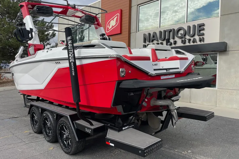 Slide: The Image of 2023 Nautique Super Air Nautique G25 Paragon boat in red and white, parked outside dealership. - 3