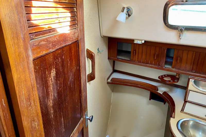 Slide: The Image of Interior of 1994 Island Packet 44 sailboat with wooden cabinetry and porthole window. - 100