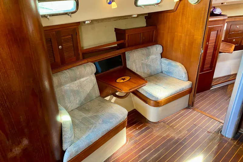 Slide: The Image of 1994 Island Packet 44 yacht interior with wooden finishes and cushioned seating. - 103