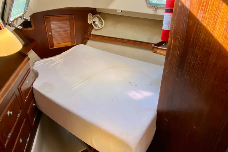 Slide: The Image of 1994 Island Packet 44 yacht cabin with bed, wooden cabinetry, and porthole window. - 109