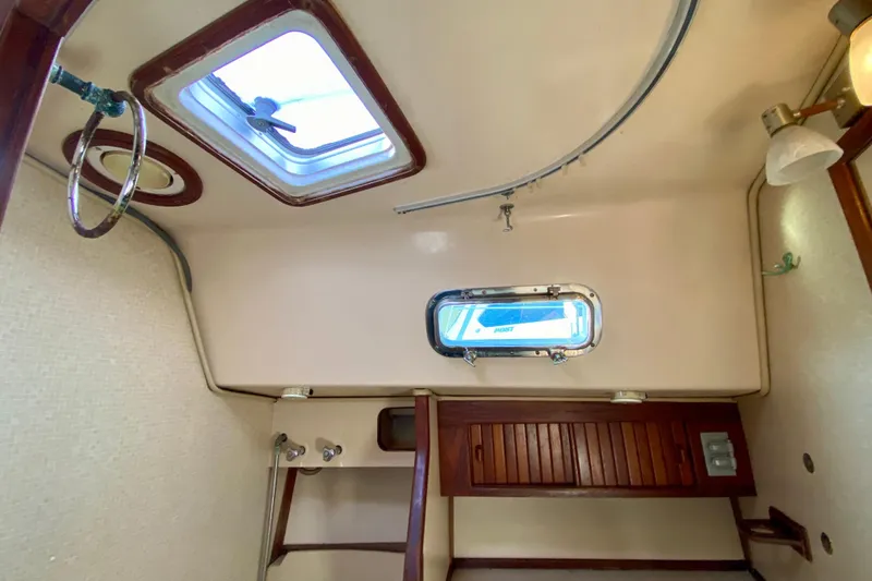 Slide: The Image of Interior of 1994 Island Packet 44 sailboat with porthole and wooden cabinetry. - 116