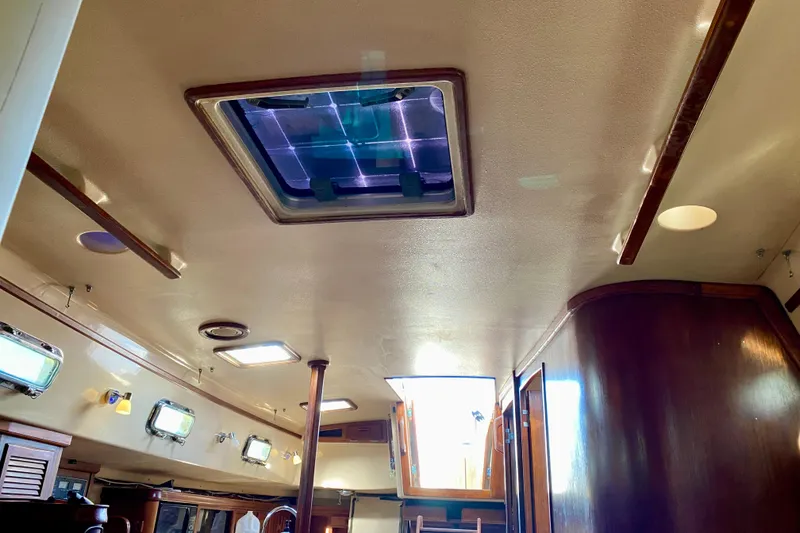 Slide: The Image of Interior view of 1994 Island Packet 44 sailboat, featuring wooden finishes and ceiling hatches. - 121