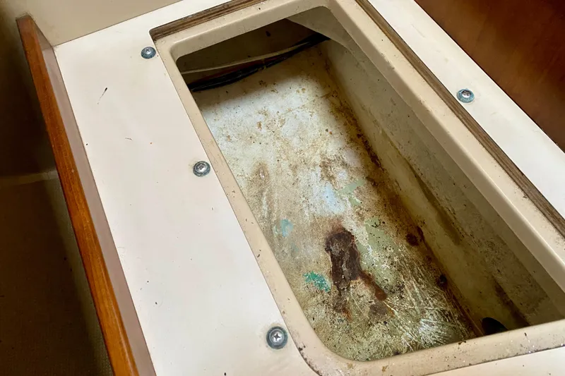 Slide: The Image of Storage compartment on a 1994 Island Packet 44 sailboat, showing wear and rust. - 128