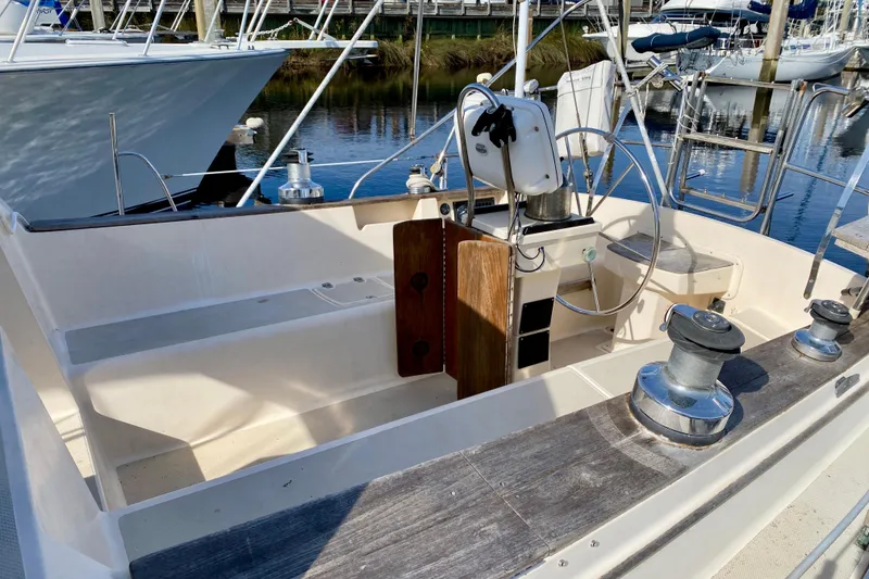 Slide: The Image of 1994 Island Packet 44 sailboat cockpit with steering wheel and winches, docked at marina. - 16