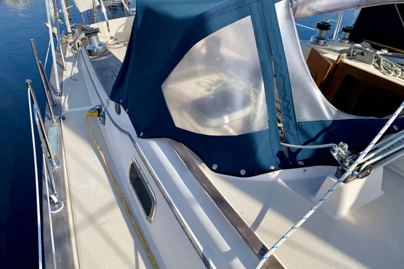 Slide: The Image of 1994 Island Packet 44 sailboat deck with blue canvas cover and winches. - 19