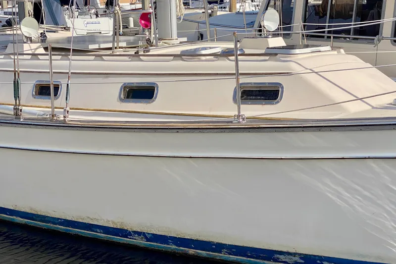 Slide: The Image of 1994 Island Packet 44 sailboat with white hull and blue trim, docked at marina. - 3