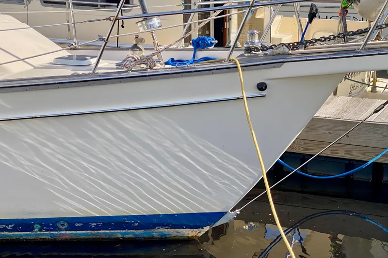 Slide: The Image of Close-up of 1994 Island Packet 44 sailboat bow with docked reflections. - 4
