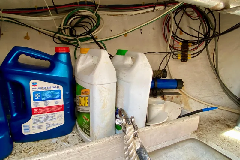 Slide: The Image of Storage compartment of a 1994 Island Packet 44 with oil containers and wiring. - 44