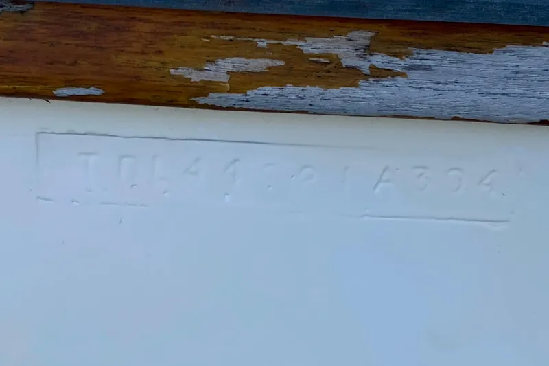 Slide: The Image of Hull identification number on 1994 Island Packet 44 sailboat with weathered wood trim. - 49
