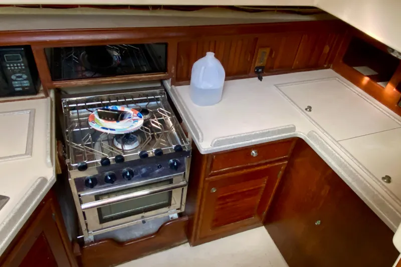 Slide: The Image of 1994 Island Packet 44 yacht kitchen with stove, wooden cabinets, and countertop. - 65