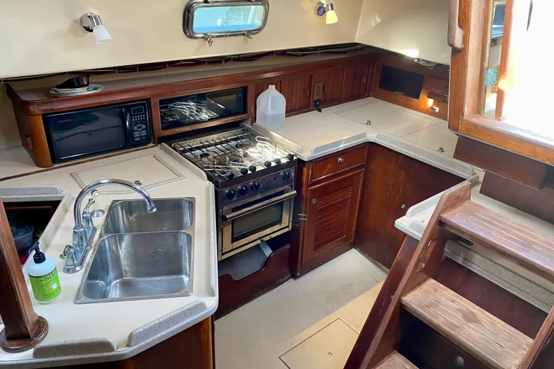 Slide: The Image of 1994 Island Packet 44 yacht kitchen with stove, sink, and wooden cabinetry. - 67