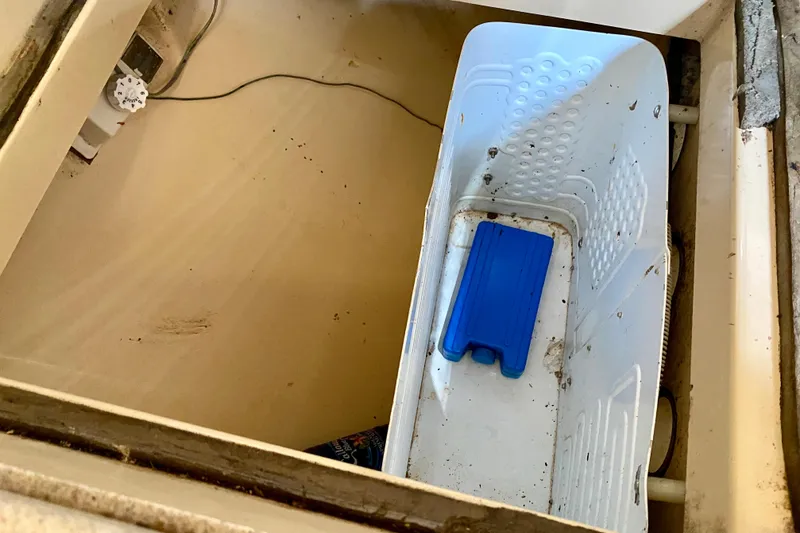 Slide: The Image of Storage compartment on a 1994 Island Packet 44 sailboat with a white plastic container. - 75