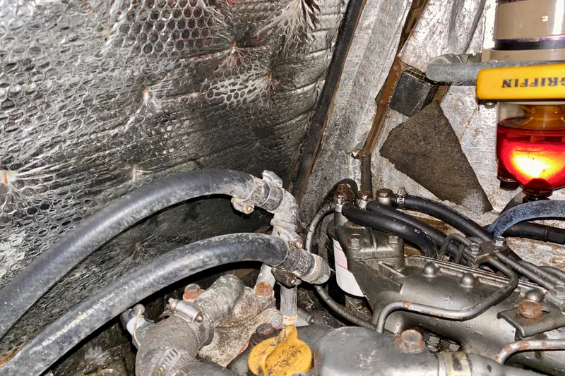 Slide: The Image of Engine compartment of a 1994 Island Packet 44 sailboat, showing hoses and mechanical components. - 87