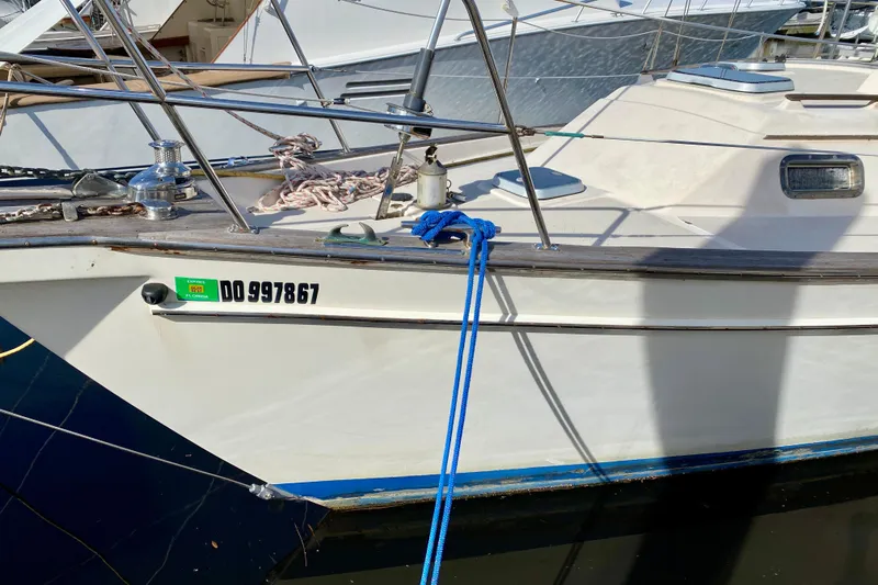 Slide: The Image of 1994 Island Packet 44 sailboat docked, featuring registration number DO997867 and blue mooring line. - 9