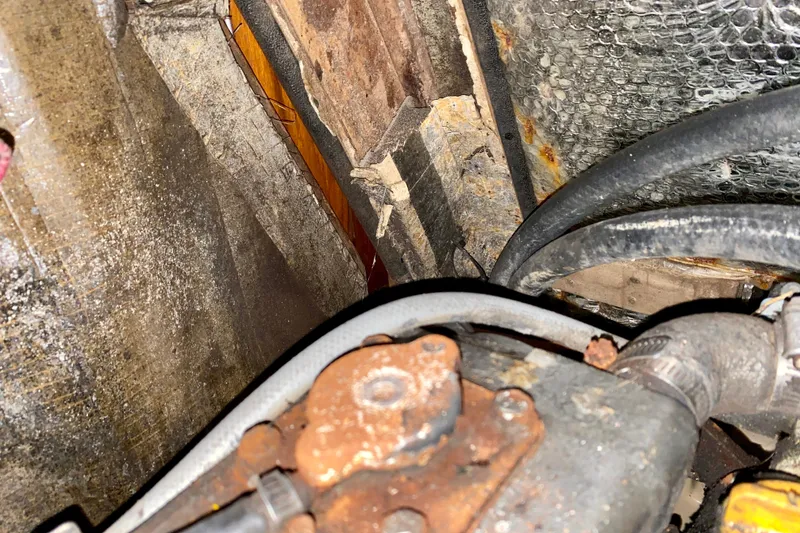 Slide: The Image of Engine compartment of a 1994 Island Packet 44 sailboat, showing rust and cables. - 96