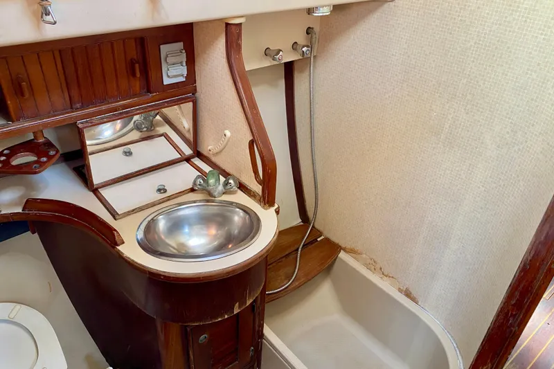 Slide: The Image of 1994 Island Packet 44 yacht bathroom with sink, shower, and wooden cabinetry. - 98