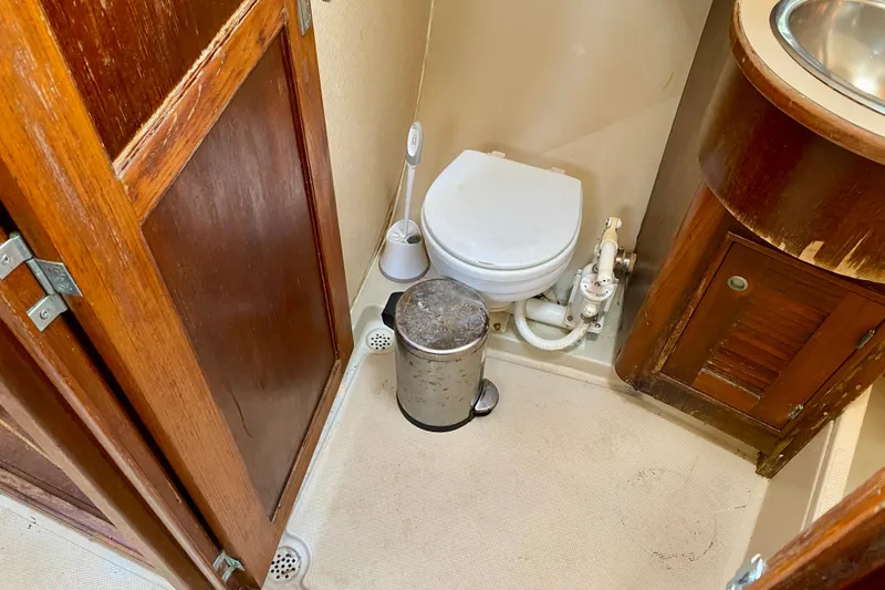 Slide: The Image of 1994 Island Packet 44 yacht bathroom with wooden cabinets and marine toilet. - 99