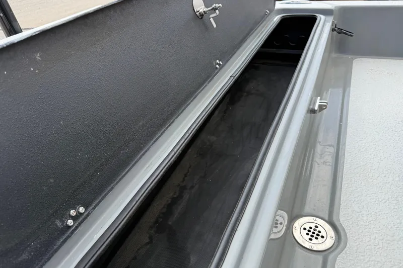 Slide: The Image of 2018 SCB Stingray boat storage compartment with open lid and drain plug. - 36