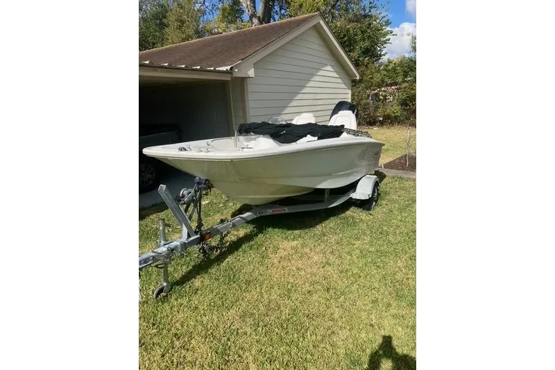Slide: The Image of 2010 Boston Whaler 13 Dauntless boat on trailer, parked beside a garage. - 1