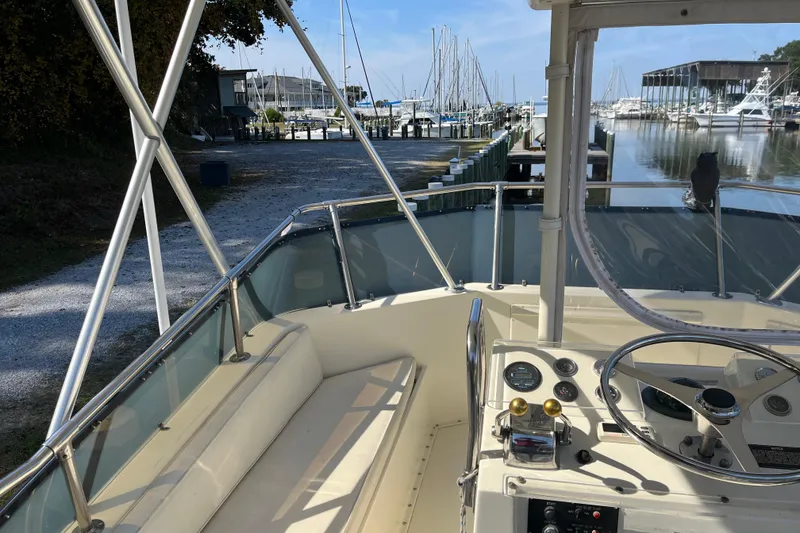 Slide: The Image of 1987 Hatteras 41 Convertible boat interior at marina, showcasing helm and seating area. - 14