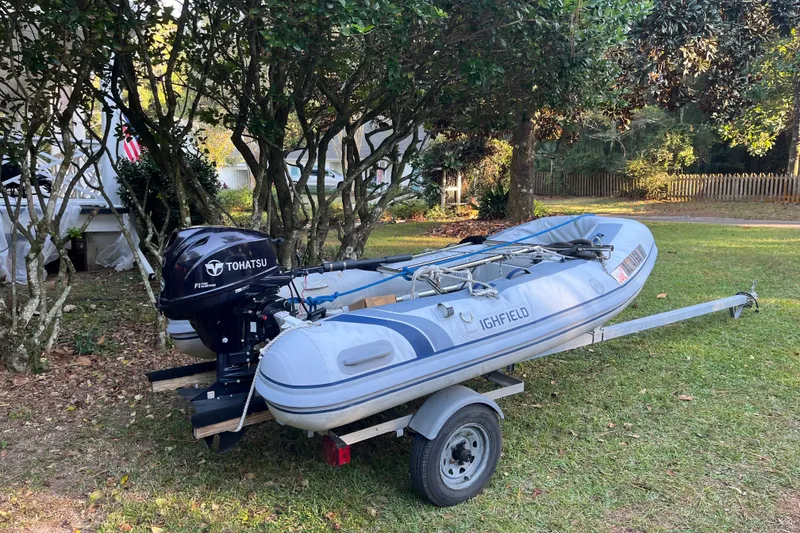 Slide: The Image of Inflatable boat with Tohatsu motor on trailer, parked on grass near trees. - 19